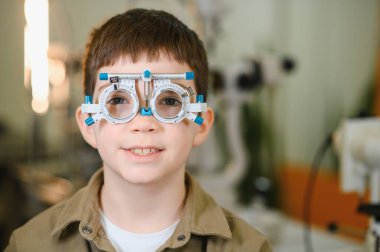 Göz doktorunun muayenehanesinde göz muayenesi yapılırken mahkeme çerçevesi takan gülümseyen çocuk, görme sağlığına odaklandı.