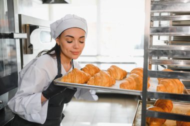 Baker, sıcak, yeni pişmiş kruvasanların enfes aromasının tadını çıkarırken, yoğun bir profesyonel mutfakta çalışıyor.