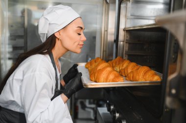 Profesyonel fırıncı, ticari bir mutfakta taze pişmiş altın kruvasan kokusunun tadını çıkarıyor.