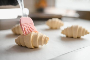 Fırında veya mutfak ortamında, fırından önce, pembe silikon fırça kullanarak, yumurta yıkama ile kruvasanları cilalamak