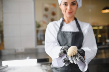 Mükemmel bir kruvasan sunan profesyonel fırıncı, bir fırın ortamında çalışmalarının kalitesini ve işçiliğini vurguluyor.