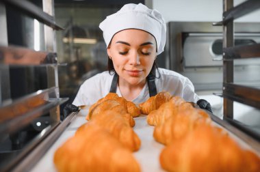 Fırıncı kapalı gözlerle kokluyor. Fırındaki bir tepside taze pişmiş kruvasan kokusu.