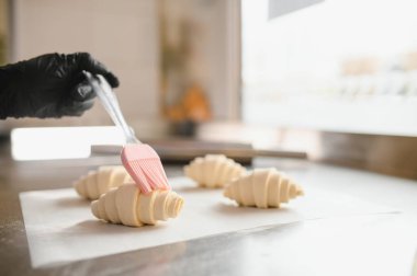 Fırıncı pişirmeden önce çiğ kruvasan üzerine yumurta fırçalamak, hamur işlerine altın bir renk ve ışıltı katmak