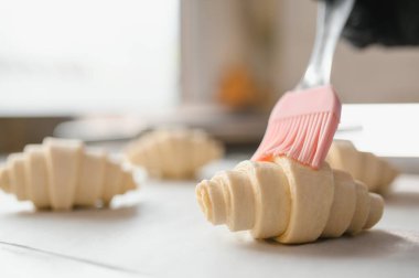 Fırıncının kruvasan hamuruna sürtündüğü yakın çekim, profesyonel fırın mutfağında hamur işleri hazırlıyor.