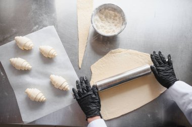 Baker, metal bir masanın üzerine ustalıkla hamur serpiyor. Taze kruvasan yapmaya hazırlanıyor. Kusursuz hareketler ve profesyonel beceriyle.