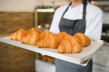 Baker, fırın mallarının kalitesini ve tazeliğini gözler önüne seren mükemmel bir tepsi altın rengi kruvasan sunar.