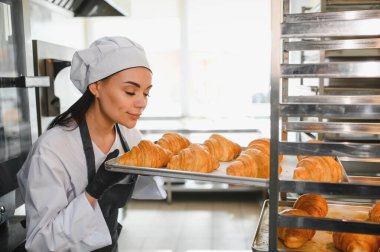 Bir fırının mutfağından taze pişmiş altın kruvasan kokusu alan profesyonel bir fırıncı.