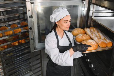 Siyah eldiven giyen profesyonel fırıncı fırından fırından taze fırın tepsisi alıyor.