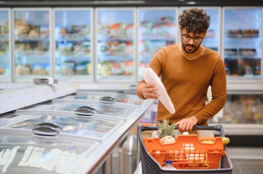 Müşteri dondurulmuş gıda reyonundan yiyecek seçiyor. Yemek hazırlamak için sağlıklı seçimler yapıyor.