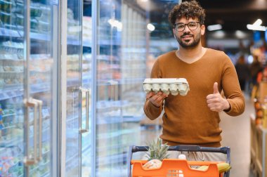 Müşteri markette alışveriş yaparken taze yumurtalardan memnun olduğunu ifade ediyor, raflardaki kalitenin ve çeşitliliğin tadını çıkarıyor