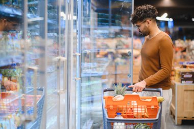 Müşteri dondurulmuş yiyecek alıyor, süpermarkette alışveriş arabası satıyor, buzdolabında yiyecek seçiyor.