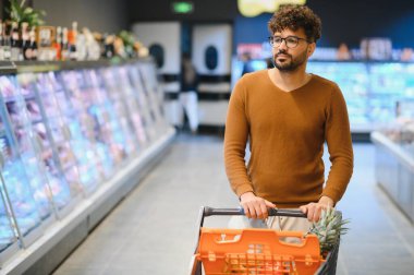 Genç Arap adam markette alışveriş arabasını iterken market alışverişi yaparken, dondurulmuş bölümde yürürken...