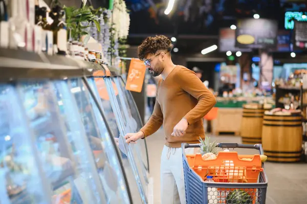 Müşteri, iyi organize edilmiş bir markette dondurulmuş yiyecekleri dondurulmuş bir vitrinden seçiyor ve uygun bir alışveriş deneyiminin keyfini çıkarıyor.