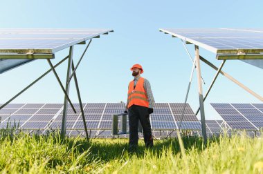 Güneş enerjisi santralinde yürüyen bakım mühendisi kurulum ve onarım için ekipman taşıyor, sürdürülebilir enerjinin geleceği
