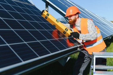 Mühendis, yeşil enerji geçişi üzerinde çalışan büyük bir fotovoltaik güç istasyonuna güneş panelleri kurarken seviye aracı kullanıyor