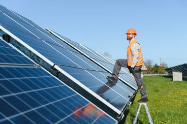 Güneş panelleri kuran, güneşli bir ortamda yeşil enerjiyi ve sürdürülebilir uygulamaları destekleyen bir merdivende çalışan erkek işçi.