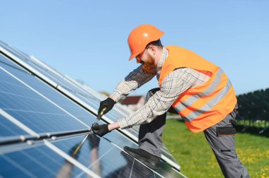 Güneşli bir günde tornavida kullanarak büyük bir güneş enerjisi santralinde güneş panelleri kurulumu üzerinde çalışan mühendis.