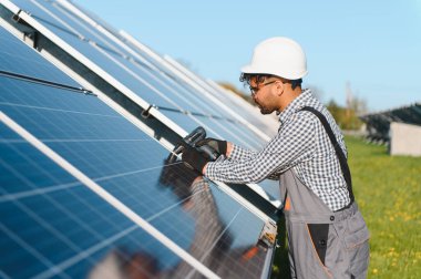 Bir tornavida kullanarak büyük bir fotovoltaik tesiste güneş panelleri kurulumu üzerinde çalışan Ortadoğu mühendisi