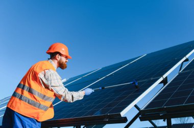 İşçi güneş panellerini özel bir araçla temizliyor, maksimum enerji verimliliğini sağlıyor ve sürdürülebilir uygulamaları destekliyor