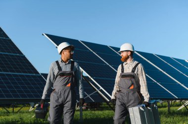 Güneş panelleri arasında yürüyen ve konuşan iki mühendis büyük bir güneş çiftliğinde