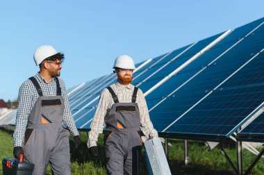İki mühendis güneş paneli çiftliğinde araç ve ekipman taşıyorlar, bakım ve onarım yapıyorlar.