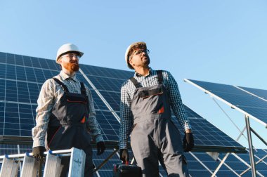 Bir enerji santraline güneş panelleri kurarak yenilenebilir enerji ve sürdürülebilirliğe katkıda bulunan iki mühendis