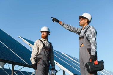 Bir güneş enerjisi istasyonuna güneş panelleri kurmak için çalışan iki mühendis yenilenebilir enerjiye katkıda bulunuyor.