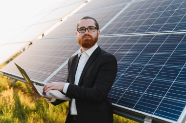 Bir dizüstü bilgisayardaki fotovoltaik güneş panellerini analiz eden işadamı, yenilenebilir enerji yatırımları ve sürdürülebilir teknoloji çözümlerine odaklanıyor