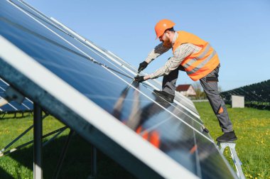 Erkek teknisyen, yenilenebilir enerji ve sürdürülebilir bir gelecek sağlamak için büyük bir güneş çiftliğinde güneş panelleri kurulumu üzerinde çalışıyor.