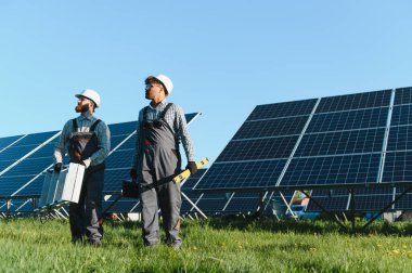 Yeşil alana güneş panelleri yerleştirmeye çalışan iki mühendis, temiz enerji ve sürdürülebilir gelişime katkıda bulunuyorlar.