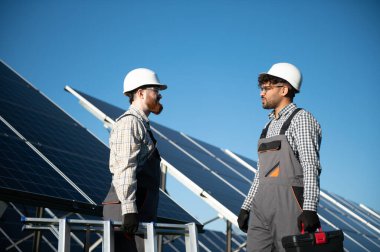 İki mühendis, elektrik santralindeki fotovoltaik güneş panellerinin montajı ve bakımı hakkında konuşuyor.
