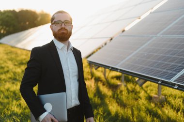 Bir güneş enerjisi santralindeki fotovoltaik panellerin performansını değerlendiren yatırımcı, sürdürülebilirlik ve temiz teknolojiye odaklanıyor