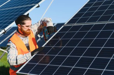 Büyük güneş enerjisi istasyonuna güneş panelleri kuran, sürdürülebilir yeşil enerji üreten tornavidayla çalışan mühendis