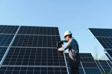 Ekolojik fotovoltaik enerji üzerinde çalışan mühendis büyük bir güneş enerjisi santraline güneş panelleri kurmak için tornavida kullanıyor.