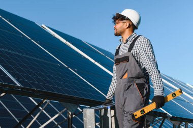 Bir güneş enerjisi santralinde çalışırken, yenilenebilir enerji ve sürdürülebilir kalkınmaya katkıda bulunan orta doğu mühendisi bir seviye tutuyor