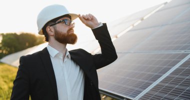 Yatırımcı, güneş paneli çiftliğini gün batımında teftiş ederken, miğferine dokunurken, sürdürülebilir enerji gelişimine daldı.