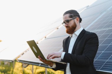 İş adamı, sürdürülebilir enerji santralinde güneş panellerini analiz ederek, daha yeşil bir gelecek için yenilenebilir enerjiye yatırım yapıyor.
