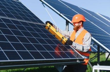 Mühendis, yenilenebilir enerji üzerinde çalışarak, bir güneş enerjisi istasyonuna güneş panelleri kurarken seviye aracı kullanıyor