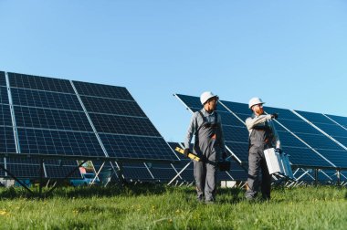 İki mühendis büyük bir alana fotovoltaik güneş panelleri kurup, yenilenebilir enerji ve çevre dostu çözümler geliştirmeyi tartışıyor.