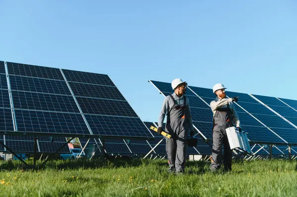 İki mühendis büyük bir alana fotovoltaik güneş panelleri kurup, yenilenebilir enerji ve çevre dostu çözümler geliştirmeyi tartışıyor.