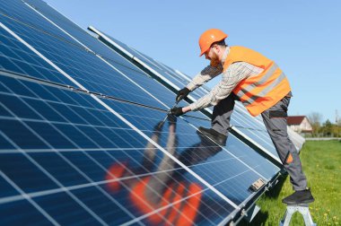 Güneşli bir günde güneş panelleri kuran işçiler, yenilenebilir enerji ve sürdürülebilir uygulamaları teşvik ediyorlar
