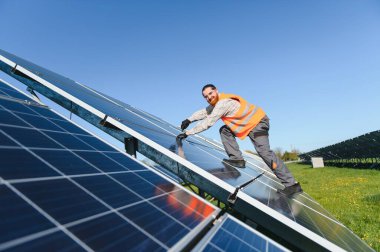 Bir güneş enerjisi santralinde fotovoltaik paneller üzerinde çalışan mühendis, cıvataları sıkıyor ve verimli enerji üretimini sağlıyor