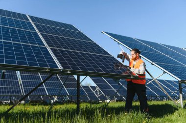 Erkek mühendis bir güneş enerjisi istasyonuna fotovoltaik paneller kuruyor, yeşil enerji geçişi üzerinde çalışıyor