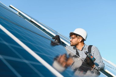 Orta doğu mühendisi tornavida kullanarak çatıya fotovoltaik paneller kuruyor ve yenilenebilir enerji geliştirme üzerinde çalışıyor.