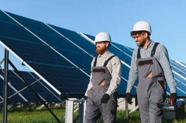 İki çok ırklı mühendis bir güneş enerjisi santralinde yürüyor, araçlar taşıyor ve yenilenebilir enerji için sürdürülebilir teknoloji üzerinde çalışıyorlar.