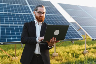 Yenilik ve yeşil enerji çözümlerini temsil eden sürdürülebilir enerji yatırımı için güneş paneli çiftliğini analiz eden bir iş adamı