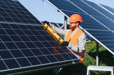 Mühendis, bir güneş enerjisi istasyonuna güneş panelleri kurulumu sırasında yeşil enerjiyi kullanan bir seviye aracı kullanıyor.