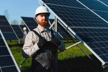 Koruyucu ekipmanlı erkek işçi güneş panelleri kuruyor, sürdürülebilir enerji çözümlerini destekliyor. Yenilenebilir enerji ve çevre dostu uygulamalara odaklanın