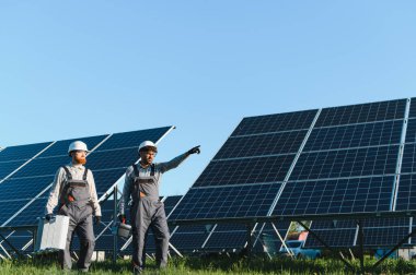 Güneş enerjisi santralinde çalışan iki mühendis, sürdürülebilir bir gelecek için yenilenebilir enerjiyi kullanırken ustalıkla güneş panelleri kuruyorlar.