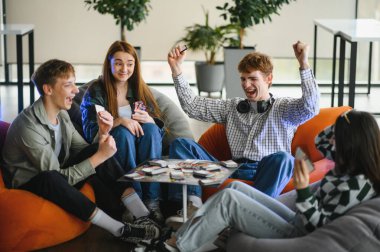 Dört neşeli genç armut koltukta oturup masa oyunu oynuyor ve birlikte eğleniyorlar.